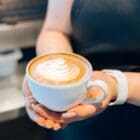 Latte art in a mug held by a coffee shop barista